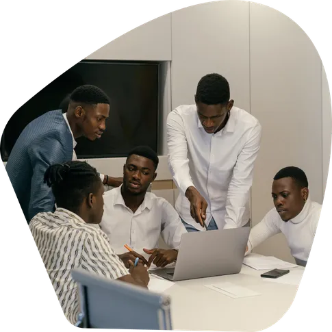 Five colleagues gathered around a laptop in a meeting room