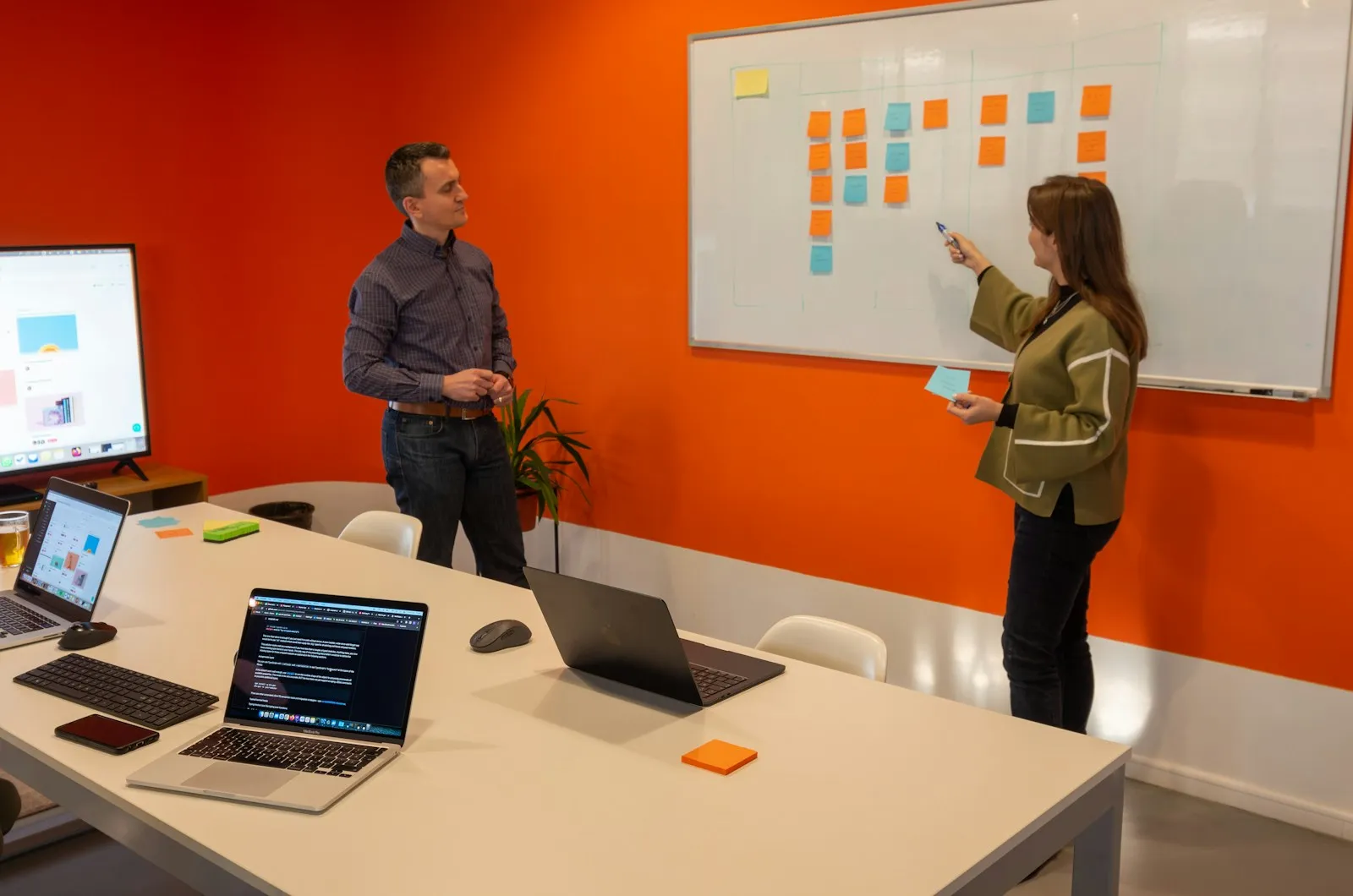 Two colleagues planning a campaign in front of a whiteboard covered in sticky notes